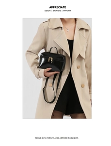 Detail of black oil-wax leather handbag with gold zippers and adjustable shoulder strap