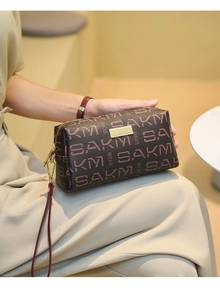 Detail of vintage textured clutch with pink monogram print and gold zipper hardware