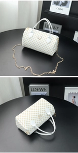 Detail of white Boston bag with gold logo print, butterfly buckle, and metal chain