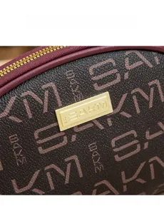 Gros plan sur la texture cuir monogramme marron foncé et la plaque en métal doré