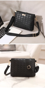 Detailed macro view of black woven texture and golden zipper hardware on the shoulder bag