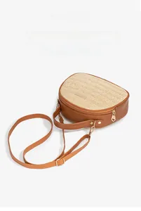 Detailansicht der halbkreisförmigen Strohtasche mit braunem Leder und Goldreißverschluss