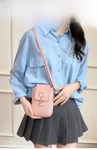 Petit sac bandoulière rose avec anneau chat et pompon perle porté par un mannequin