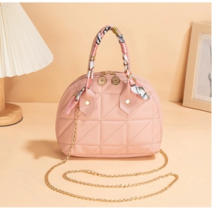 Detail of pink quilted shell bag with silk scarf handle and gold chain strap