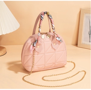 Detail of pink quilted shell bag with silk scarf handle and gold chain strap