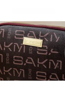 Detail of coffee brown patterned bag with gold logo plate and textured leather trim