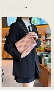 Pink flap chain bag with geometric prints and gold hardware styled in a cafe setting