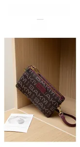 Detailed view of dark burgundy printed wallet with double zippers and wrist strap
