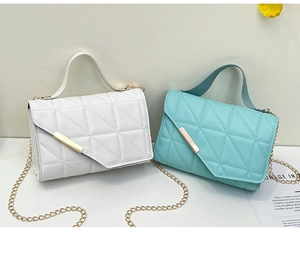 Detail of quilted cross-body bags in white and mint green with gold chain straps