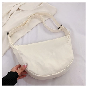 Détail d'un sac bandoulière demi-lune blanc crème avec texture côtelée et sangle