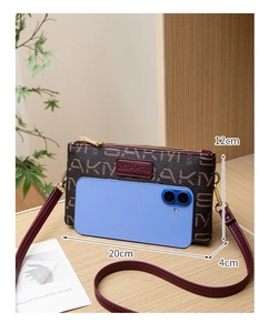 Detail of vintage crossbody bag showing dimensions and phone capacity on wood surface