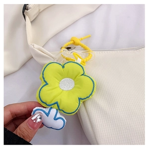 Détail d'un pendentif fleur en peluche jaune et nuage blanc sur un sac à bandoulière blanc
