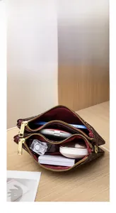 Internal view of a multi-layer brown floral patterned crossbody bag with three zipper pockets