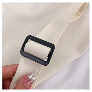 Détail de la boucle réglable noire sur une bandoulière en toile blanc cassé pour sac