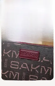 Detailed macro view of dark brown leather texture with BAKM letter print and gold zipper