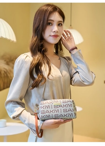 Detail of vintage beige clutch bag featuring burgundy monogram print and gold logo plate