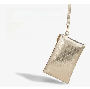 Detail of a gold quilted wristlet bag featuring a metallic finish and square texture