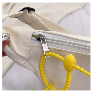 Détail du zip métallique et du cordon jaune sur le sac à bandoulière beige tendance