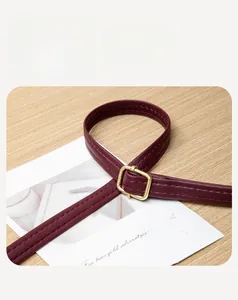 Detail of burgundy leather shoulder strap with golden buckle and fine stitching