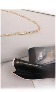 Detail view of pink handbag featuring gold chain strap and spacious black interior