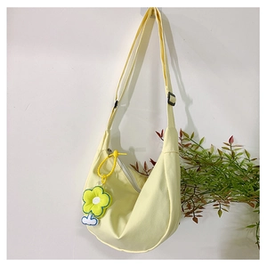 Détail du sac croissant en toile jaune clair avec un pendentif décoratif en forme de fleur