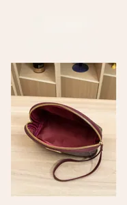 Détail du mini sac imprimé monogramme avec doublure rouge et fermeture éclair dorée