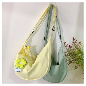 Détail de sacs bandoulière demi-lune jaunes et verts avec un pendentif fleur de tournesol