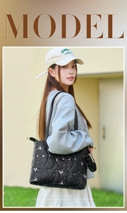 Outdoor shot of a black quilted tote with pink floral embroidery and a matching mini pouch