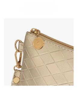 Close-up of champagne gold clutch featuring quilted texture and custom metal zipper