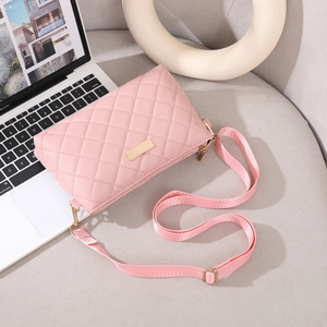 Detailed shot of pink quilted crossbody bag with gold buckle and adjustable strap