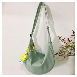 Détail du sac demi-lune vert en toile avec breloque tournesol jaune et chaîne