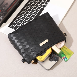 Minimalist black woven envelope bag with luxury pattern and items displayed inside