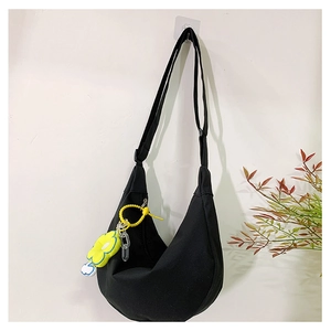 Détail du sac croissant en toile noire avec breloque fleur jaune et bandoulière