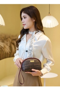 Détail d'une mini pochette à monogramme avec fermoir doré tenue par un mannequin mode