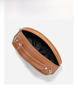 Detail einer halbrunden Stroh-Handtasche mit braunen Ledergriffen und goldenen Metallringen