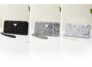 Three sequined clutch purses in black, silver, and white with butterfly metal buckles