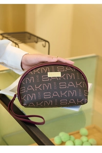 Détail d'une pochette demi-lune marron avec imprimé SAKM et dragonne de couleur bordeaux