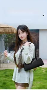 Sac baguette minimaliste en cuir noir porté à l'épaule avec une forme rectangulaire chic