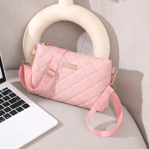 Detailed close-up of pink quilted crossbody bag with golden hardware and metal logo plate