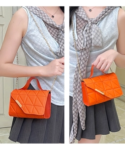 Close-up of orange quilted crossbody bag with triangle stitching and gold chain