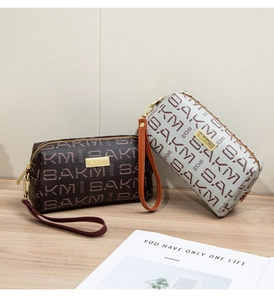 Macro detail of patterned faux leather clutch bags with metal logo and wrist straps