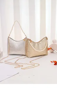 Details von silbernen und goldenen Mini-Handtaschen mit Steppmuster und Perlengriff