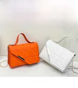 Detail of quilted leather crossbody bags in orange and white with gold chain straps
