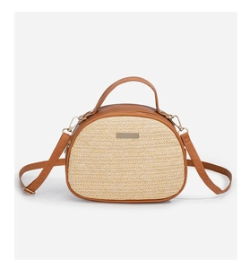 Detailansicht der gewebten Stroh-Halbrundtasche mit braunem Lederbesatz und Gold-Schnalle