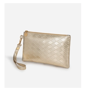 Detailed view of golden wristlet bag with textured diamond pattern and metal strap hook
