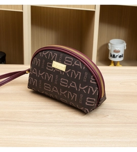 Détail d'un mini sac à main marron avec imprimé monogramme SAKM et zip doré brillant