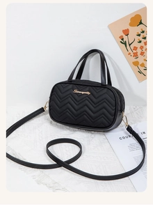 Dettaglio della trama trapuntata a V nera con logo dorato su una borsa a tracolla chic