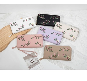 Detailed overhead view of long zipper wallets with floral embroidery and wrist straps