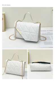Detail view of white triangle quilted bag with gold chain strap and metal trim