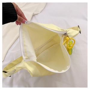 Vue de dessus d'un sac bandoulière compact en toile jaune clair avec fermeture éclair blanche